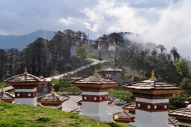 Dochula Pass with 108 memorial chortens surrounded by Himalayan mountains and prayer flags in Bhutan.