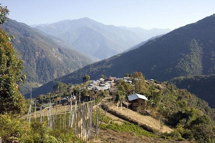 Trekker walking through the lush forests and traditional villages on the Nabji Korphu Community Trek in central Bhutan.