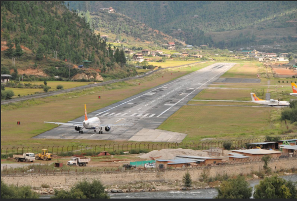 Druk Air plane parked at Paro International Airport in Bhutan, surrounded by mountains.